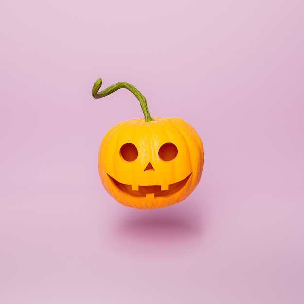 Halloween-Kürbis mit glücklichem Gesicht auf minimalem rosa Hintergrund