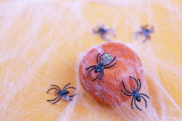 Halloween-Kürbis mit Spinnennetz und schwarzen Spinnen auf orangem Hintergrund