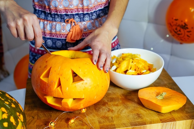 Halloween-Kürbis-Schneideprozess zur Herstellung von Jackolantern Weibliche Hände mit Messer