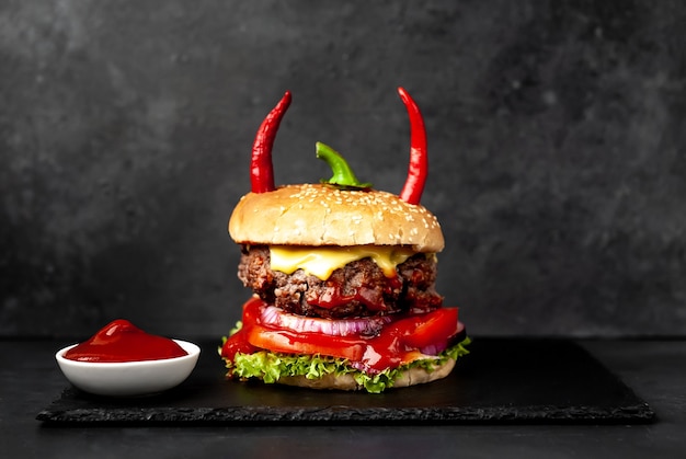 Halloween kürbisförmiger Burger mit roten Pfefferhörnern auf Steinmauer