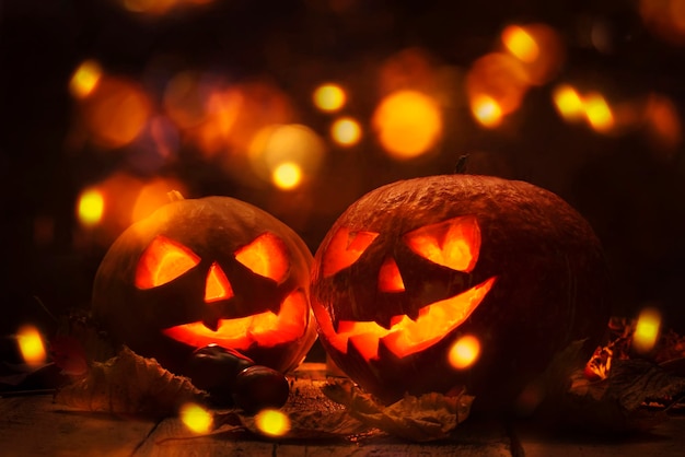 Halloween-Kürbiskopf Jack o Laterne mit brennendem Feuer Hintergrund Holztisch mit heller Bokeh-Girlande Schöne Feiertags-Herbst-Komposition