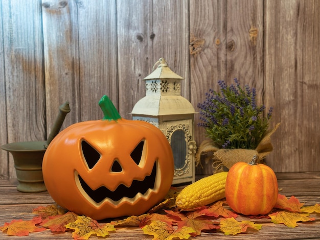 Halloween-Kürbiskopflaterne mit Kerzen und Kürbis auf Holzhintergrund