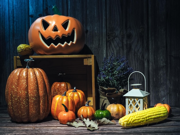 Halloween-Kürbiskopflaterne mit Kerzen und Kürbis auf Holzhintergrund