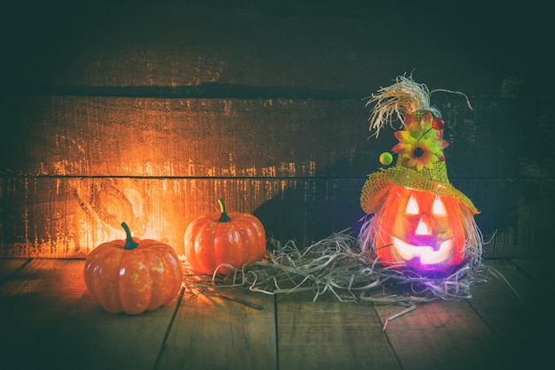 Halloween-Kürbislaterne mit trockenem Stroh auf hölzernem