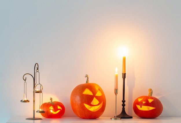 Halloween-Kürbisse mit brennenden Kerzen im weißen Innenraum