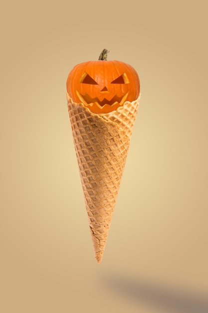Halloween-Kürbisse mit Kegeleis auf pastellbeigem Hintergrund Kreative Idee minimales Konzept Süßes Halloween-Dessert