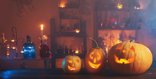 Halloween-Kürbisse mit Kerzen und Zaubertränken nachts drinnen