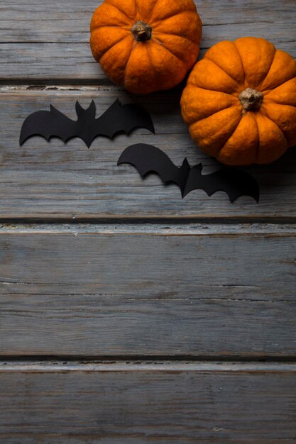 Halloween-Kürbisse und schwarze Vampirfledermäuse auf einem hölzernen Hintergrund