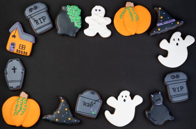 Foto halloween-lebkuchen, kürbis, katze, geist, grabstein auf schwarzem hintergrund mit kopienraum.