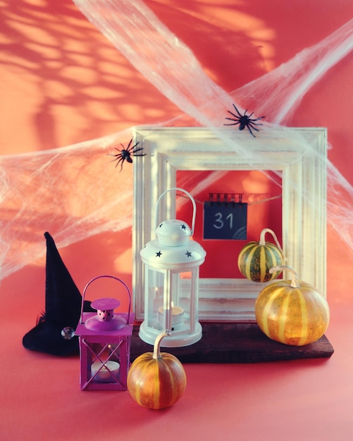 Halloween, una linterna con una vela encendida, calabazas, telarañas de sombrero de bruja con arañas