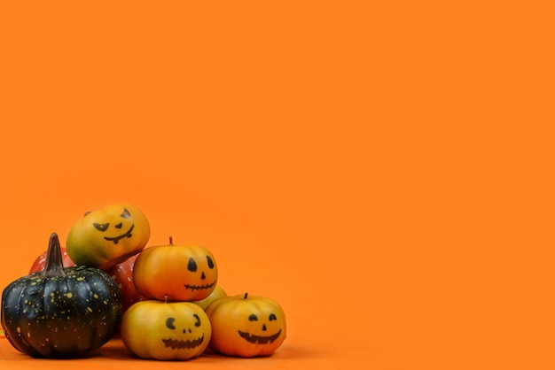 Halloween mit Kürbissen und lustigen Gesichtern auf orangefarbenem Hintergrund