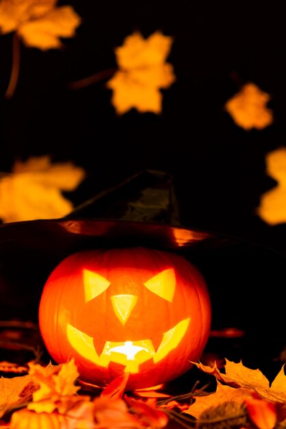 Halloween Naturaleza muerta Tema colorido Asustador Decorado Hojas de arce oscuras y amarillas Habitación con sombrero de bruja de calabaza en llamas Hojas amarillas de fondo