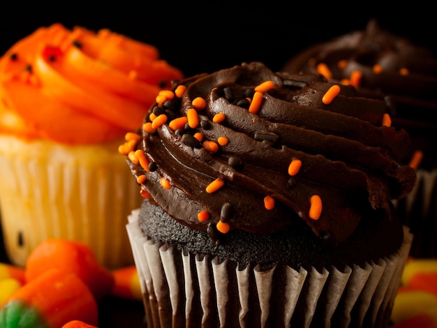 Halloween orange und schwarze Cupcakes mit Candy Corn Bonbons auf schwarzem Hintergrund.