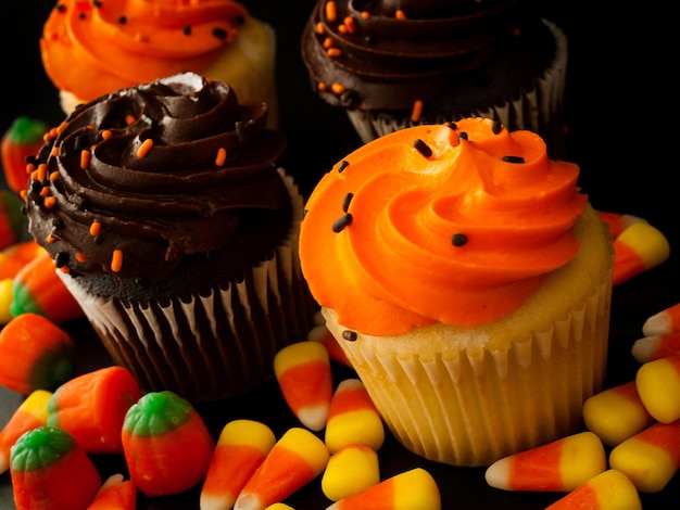 Halloween orange und schwarze Cupcakes mit Candy Corn Bonbons auf schwarzem Hintergrund.