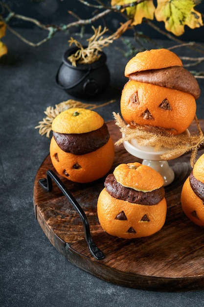 Halloween-Party Jackolantern Schokoladen-Orangen-Kuchen vor dem Hintergrund der alten Waldzweige und Blätter Halloween-Food-Konzept Süßigkeiten für die Halloween-Feier