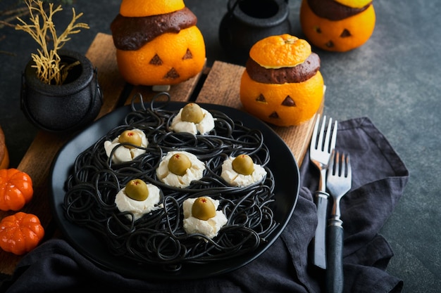 Halloween-Party Jackolantern Schokoladen-Orangen-Kuchen vor dem Hintergrund der alten Waldzweige und Blätter Halloween-Food-Konzept Süßigkeiten für die Halloween-Feier