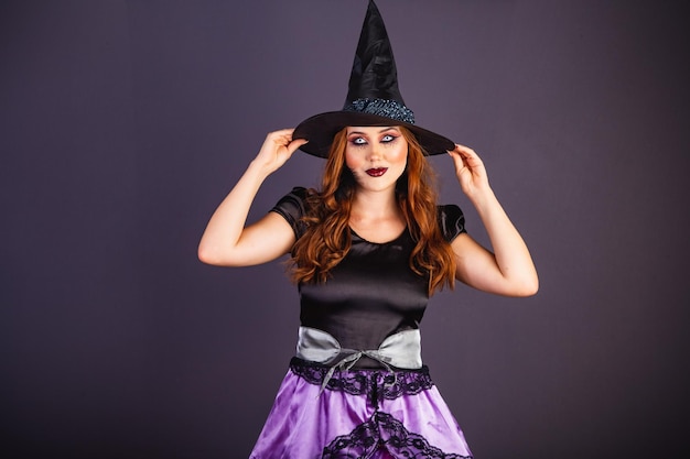 Halloween-Probe Kaukasische Frau, die Hexenkostüm mit seiner Hand auf seinem Hut trägt