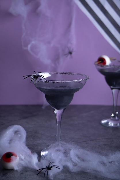 Halloween schwarzer Cocktail in Gläsern, die Spinnennetz und Süßigkeitenaugapfel schmücken Party festliches Feierkonzept