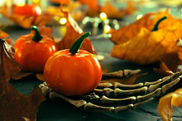 Halloween-Skeletthand mit dekorativen Kürbissen