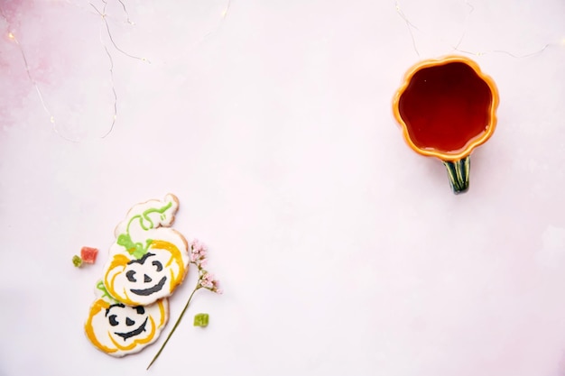 Halloween-Stillleben mit Kürbistasse mit Tee und hausgemachten Keksen in Form von süßen Kürbissen.