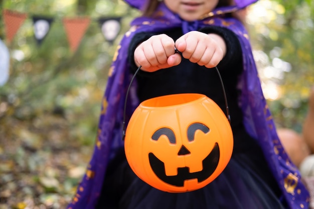 Halloween. süßes kleines mädchen im hexenkostüm mit jack o laterne, die spaß im freien hat