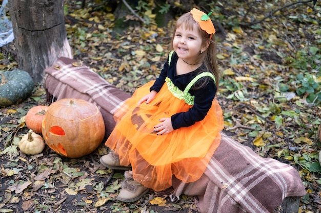 Halloween. süßes kleines Mädchen im Kürbiskostüm, das Spaß hat und Halloween im Freien feiert