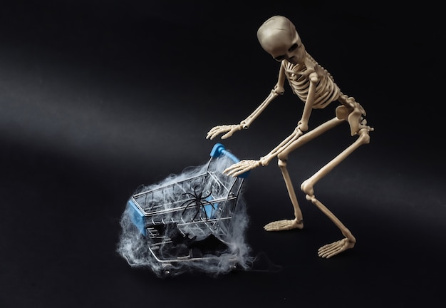 Halloween, tema de miedo. Esqueleto falso y carro de compras en web en negro.