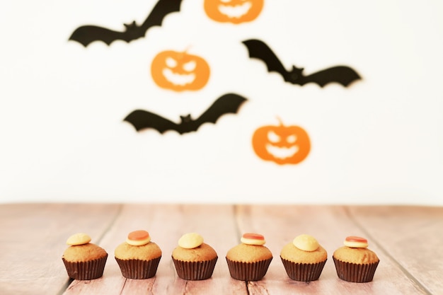 Halloween trata cupcakes en la mesa contra el fondo de calabazas y murciélagos