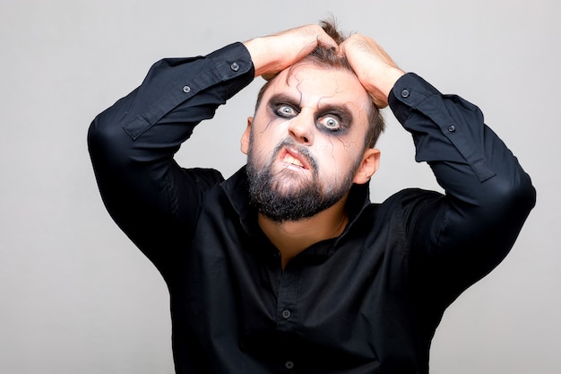 Halloween und Make-up für einen bärtigen Mann, der sich die Haare auf dem Kopf zerreißt