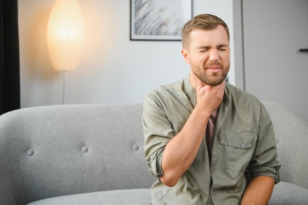 Halsschmerzen Männer mit Nackenschmerzen im Konzept der Gesundheitsprobleme im Innenbereich