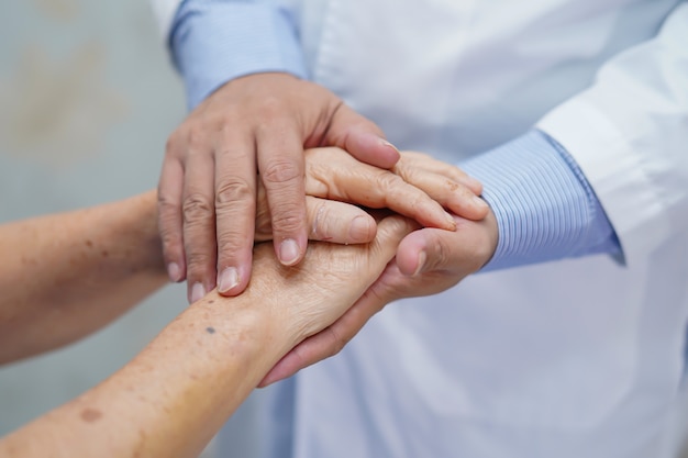 Halten des rührenden Handasiatischen älteren Frauenpatienten mit Liebe.