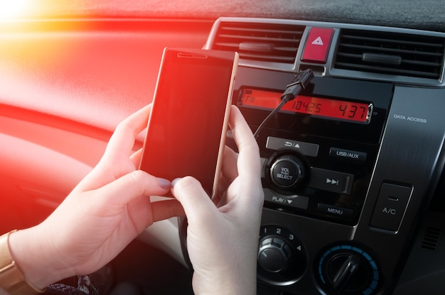 Halten Sie das Smartphone im Auto in der Hand. Menschen drücken während der Fahrt auf das Telefon