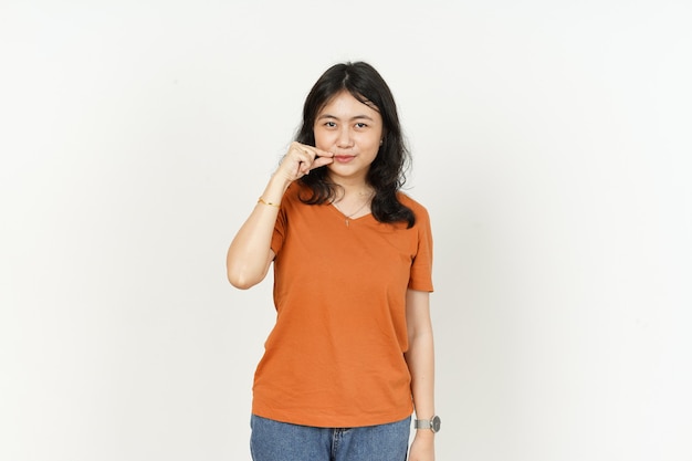 Halten Sie die geheime Lippe der schönen asiatischen Frau mit orangefarbenem T-Shirt auf weißem Hintergrund geschlossen