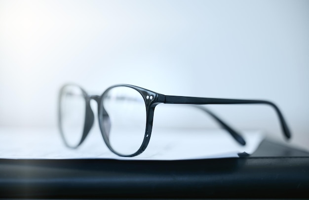 Halten Sie die Sicht frei Aufnahme einer Brille, die tagsüber in einem leeren Büro auf einem Schreibtisch liegt