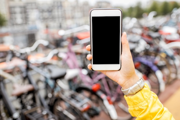Halten Sie ein Smartphone mit leerem Bildschirm, um das Einfügen auf dem Fahrradparkhintergrund zu kopieren