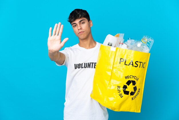 Halten Sie eine Tasche voller Plastikflaschen, um sie auf Blau zu recyceln, und machen Sie eine Stoppgeste