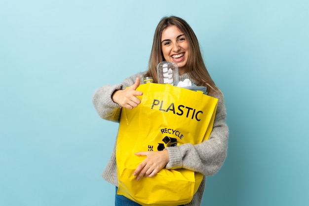 Halten Sie eine Tüte voll Plastikflaschen, um sie über einem isolierten blauen Finger zu recyceln