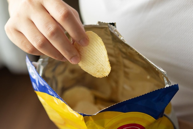 Halten Sie Kartoffelchips mit Snackbeutel in der Hand