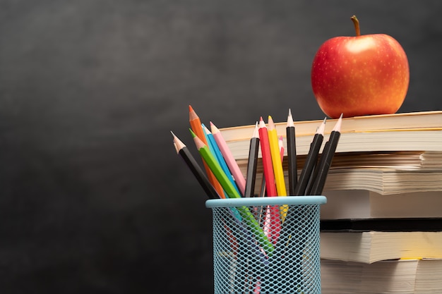 Foto halter apfel, bücher und stifthalter auf dem schreibtisch