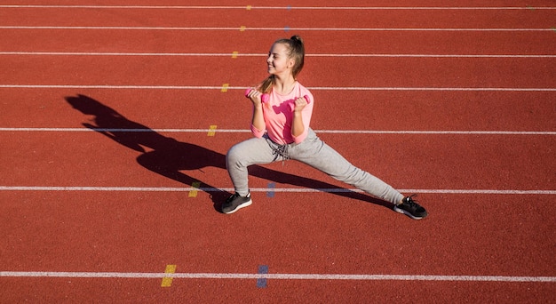 Halteres de treinamento de menina criança saudável na pista de atletismo do estádio, poder.