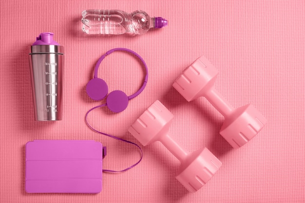 Foto halteres rosa, fones de ouvido e shaker de proteína no tapete de fitness