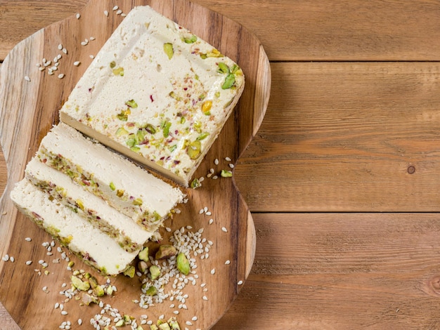 Halva de gergelim com pistache na tábua de teca em um fundo de madeira marrom Vista superior Copiar espaço