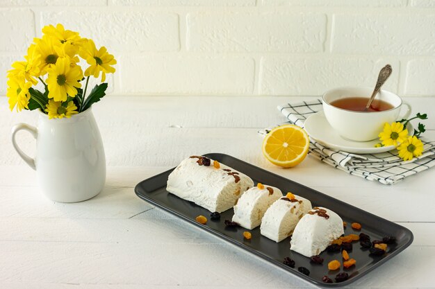 Halva con nueces servido en un escritorio de madera blanca con flores y té. desayuno de la mañana.