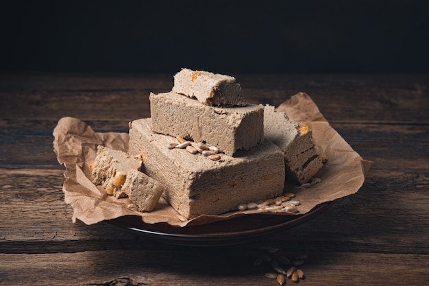 Halva-Stücke mit Erdnüssen werden mit Samen auf eine braune Dunkelheit gestreut