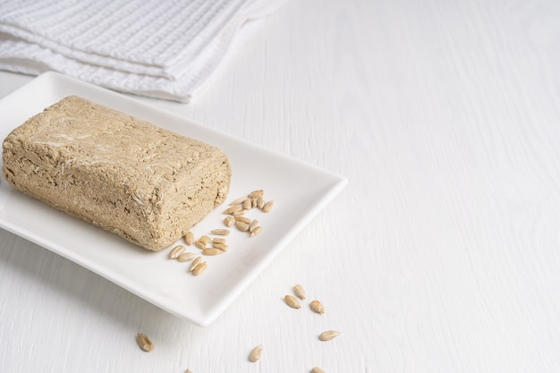 Halva, también halvah, comida dulce asiática hecha de semillas de girasol en un plato sobre una mesa blanca con textil