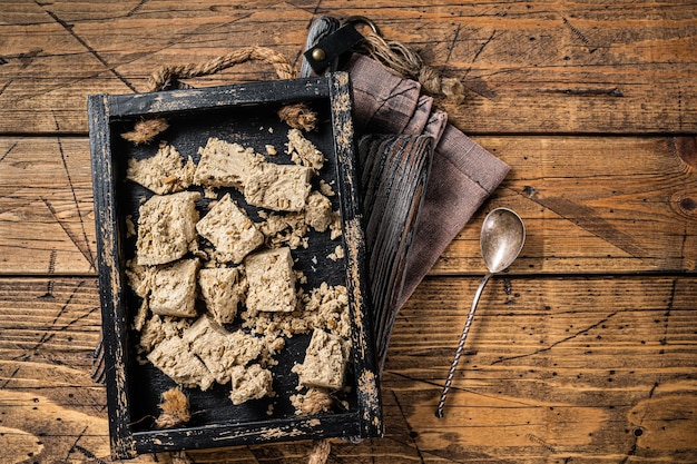 Halva turco con semillas de girasol y miel en bandeja de madera. Fondo de madera. Vista superior.