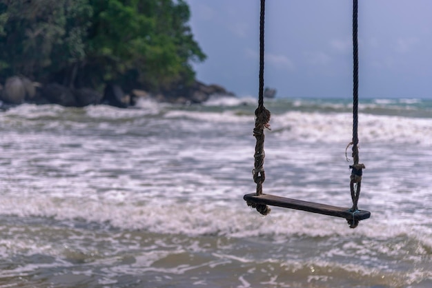 Foto hamaca colgada bajo un árbol en una playa de arena blanca y cielo azul y aguas esmeralda