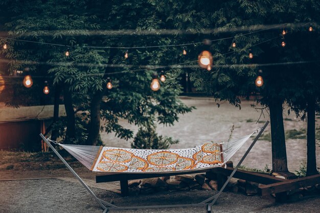 Hamaca con estilo hipster bajo luces románticas en el parque en el concepto de viaje de camping familiar resort