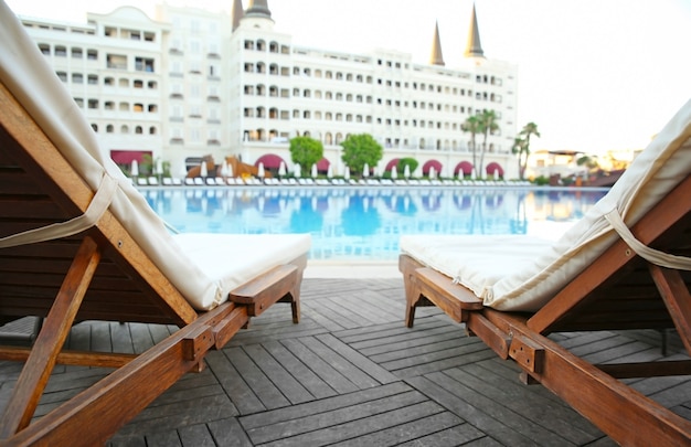 Hamacas vacías cerca de la piscina en hotel de lujo