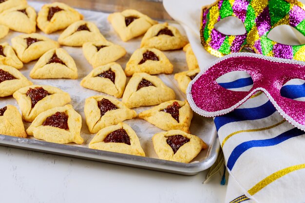 Hamantaschen biscoitos com geléia na assadeira com talit e máscara.